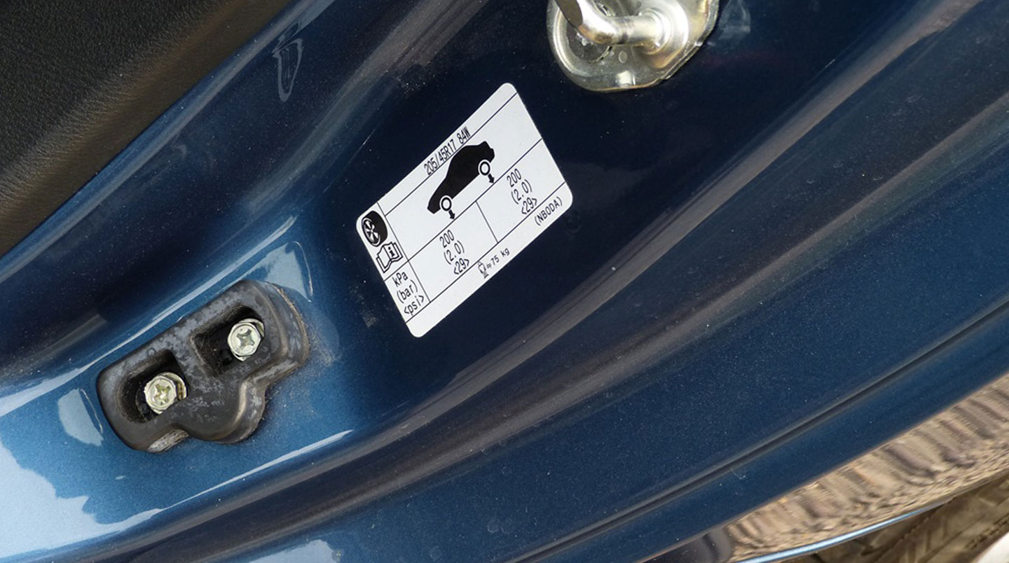 Étiquette constructeur visible sur le montant de portière d'une Peugeot 208 indiquant les dimensions de pneus recommandées